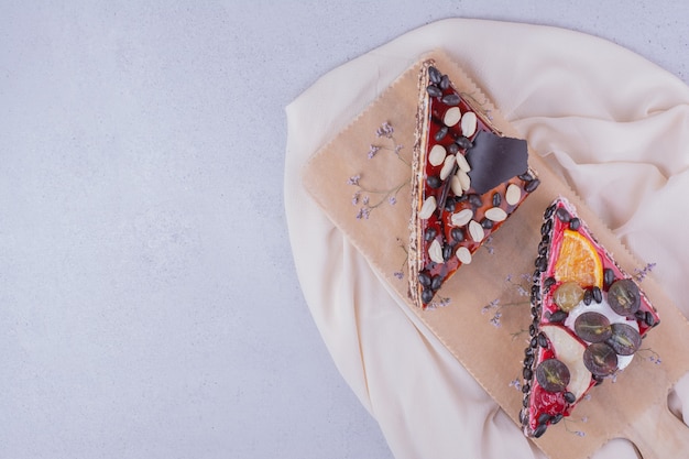 Dreieckige Schokoladenkuchenscheiben mit Nüssen und Früchten auf einer Holzplatte