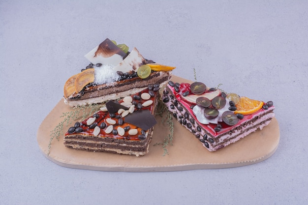 Dreieckige schokoladenkuchenscheiben mit nüssen und früchten auf einer holzplatte