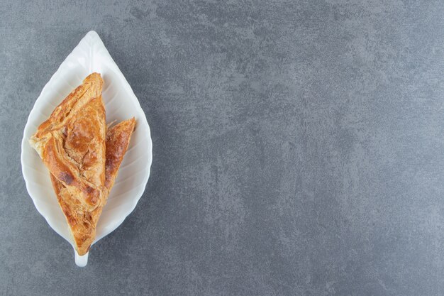 Dreieckiges Gebäck gefüllt mit Käse auf weißem Teller.