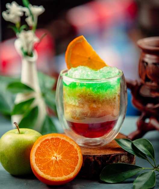 dreifarbiger exotischer Cocktail mit Apfel- und Orangensaft und Eisrasur
