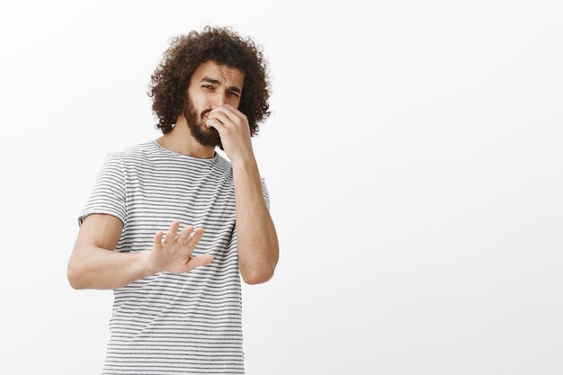 Du stinkst, komm nicht näher. Porträt eines angewiderten, ablehnenden, gutaussehenden Mannes mit Afro-Frisur, der sich nach hinten neigt und die Handfläche zum Stillstand bringt oder keine Geste