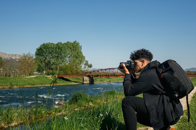 Duckender junger Mann, der Foto von flüssigem Fluss macht