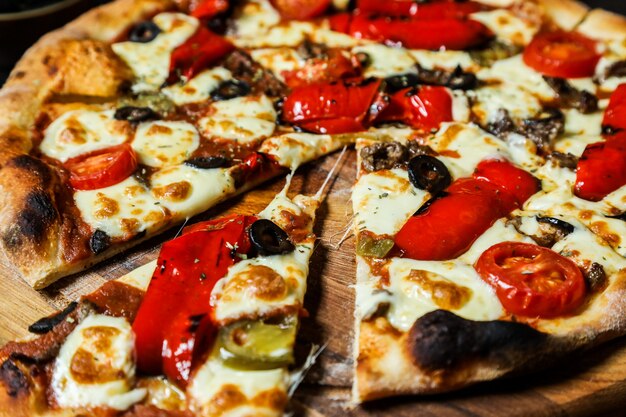 Dünne gemischte Pizza mit verschiedenen Zutaten Nahaufnahme