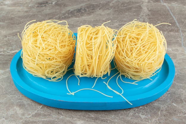 Kostenloses Foto dünne spaghetti-nester auf blauem teller.