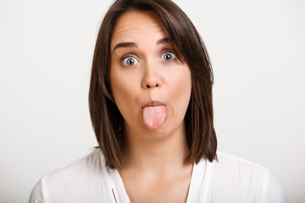 Dumme, lustige erwachsene Frau, die Zunge zeigt