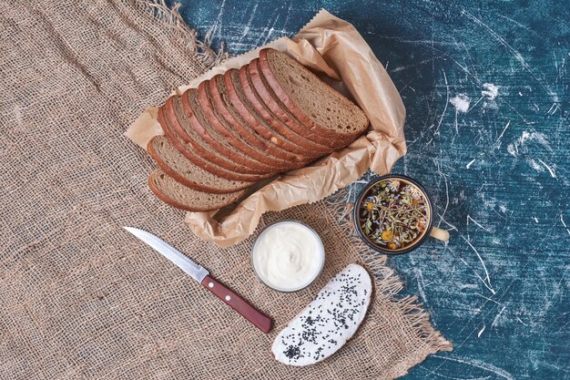 Dunkelbrotscheiben mit Sauerrahm auf Blau.