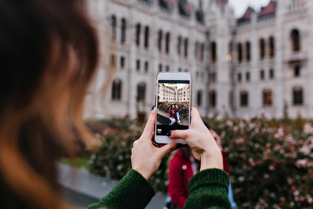 Dunkelhaarige Dame, die das Telefon für ein Bild ihrer Freundin benutzt