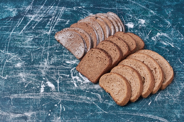 Dunkle Brotscheiben auf blauem Tisch.