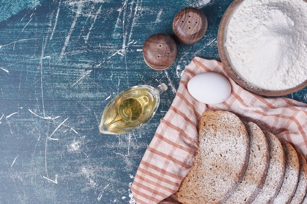 Dunkle Brotscheiben mit Eiern auf blauem Tisch.