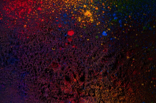 Dunkle Holi-Farben bespritzt auf schwarzem Hintergrund
