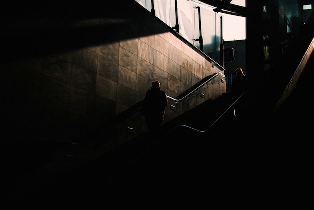 Dunkler unterirdischer Bereich mit zwei Personen, die die Treppe hinuntergehen