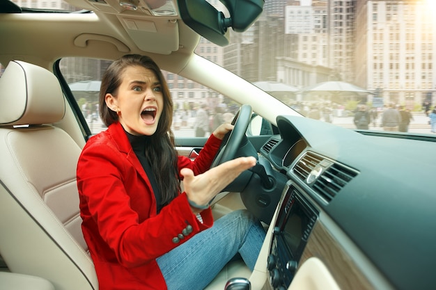 Durch die Stadt fahren. Junge attraktive Frau, die ein Auto fährt