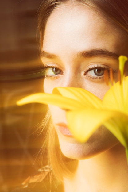 Durchdachte blonde Frau mit gelber Blume