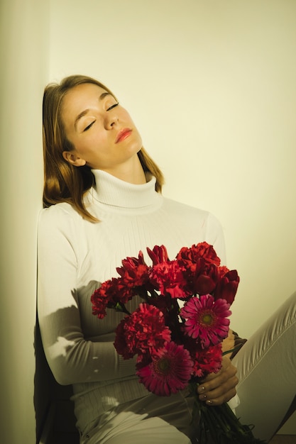 Durchdachte Frau, die mit Blumenblumenstrauß sitzt