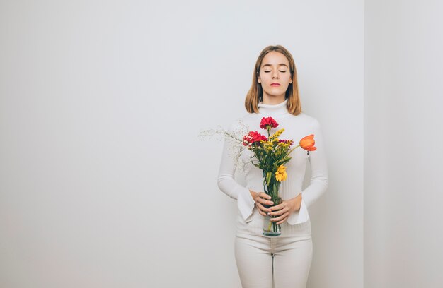 Durchdachte Frau mit hellen Blumen im Vase