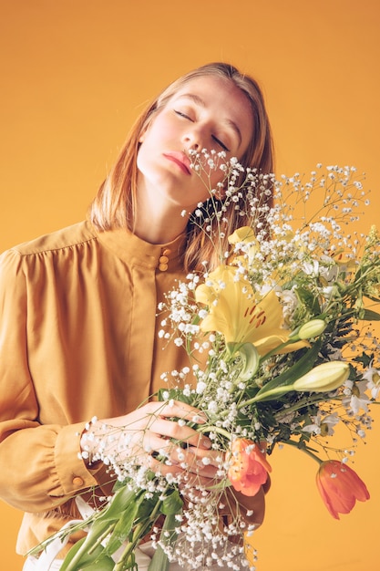 Durchdachte junge Frau, die mit Blumenblumenstrauß steht