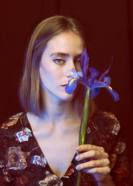 Kostenloses Foto durchdachte junge frau mit blauer blume