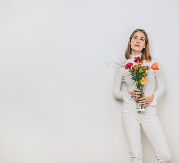 Durchdachte junge Frau mit Blumen im Vase