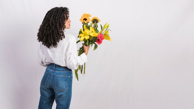 Kostenloses Foto durchdachte schwarze frau, die blumenblumenstrauß hält