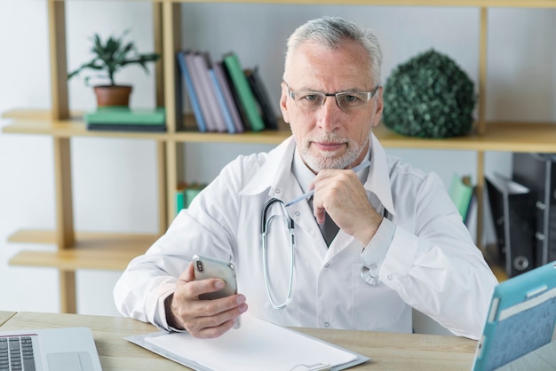 Durchdachter Doktor mit Smartphone