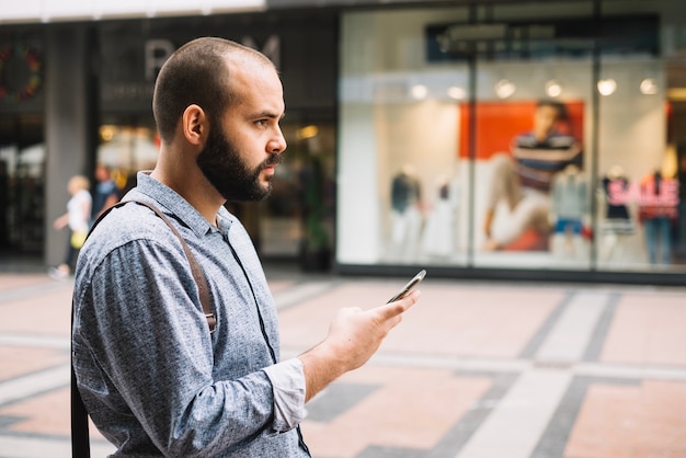 Durchdachter Geschäftsmann, der Telefon an der Straße verwendet