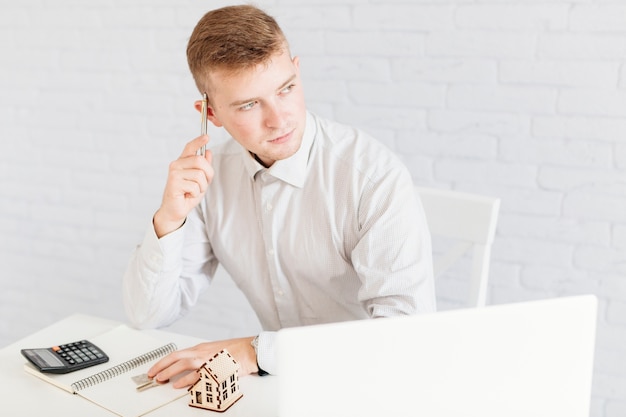 Kostenloses Foto durchdachter hübscher grundstücksmakler im büro