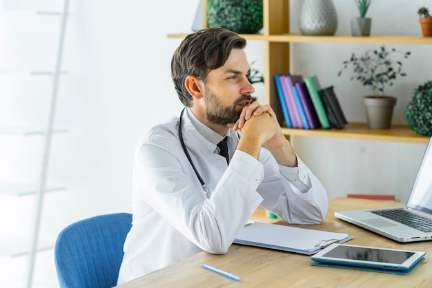 Durchdachter junger Doktor im Büro