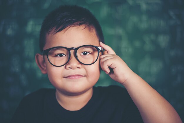 Durchdachter kleiner Junge mit Buch nahe einer Schulbehörde