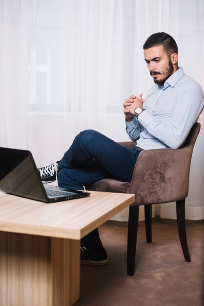 Durchdachter Mann, der am Laptop arbeitet