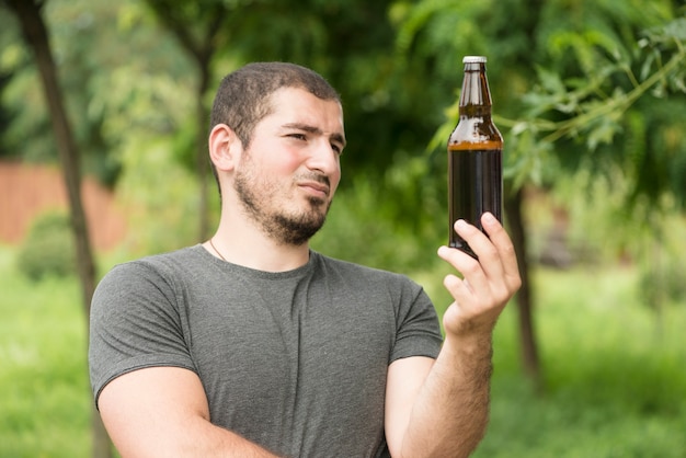 Durchdachter Mann, der Bier betrachtet