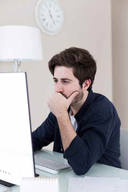 Durchdachter Mann, der Computer im Büro verwendet