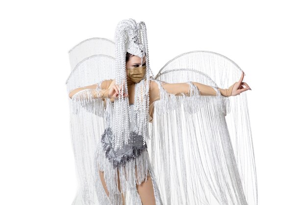 Durchführen. Schöne junge Frau im Karnevals-Maskeradenkostüm mit weißen Federn, die auf weißem Hintergrund tanzen. Konzept der Feiertagsfeier, der festlichen Zeit, des Tanzes, der Partei, des Glücks. Copyspace