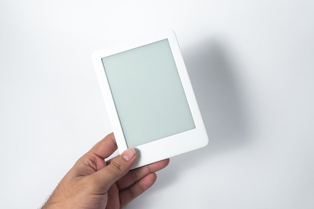 Kostenloses Foto e-book-reader über isoliertem weißem hintergrund, der von einer männlichen hand gehalten wird