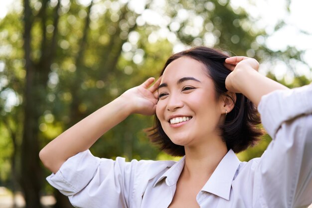 Echtes Menschenporträt einer asiatischen Frau, die lacht und lächelt und im Park spazieren geht und Freude und Positivität fühlt