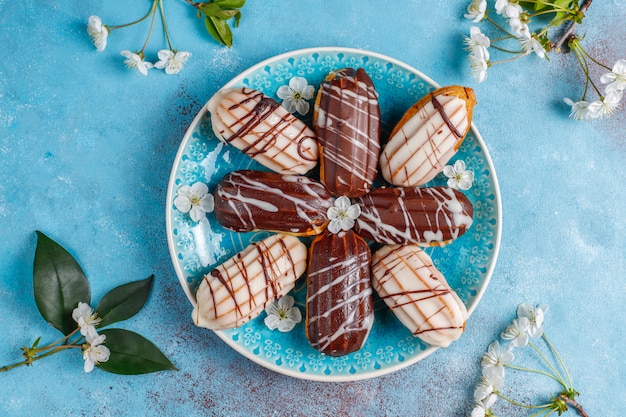 Eclairs oder Kränzchen mit schwarzer Schokolade und weißer Schokolade mit Pudding im Inneren, traditionelles französisches Dessert. Draufsicht.