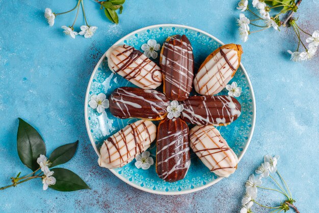 Eclairs oder Kränzchen mit schwarzer Schokolade und weißer Schokolade mit Pudding im Inneren, traditionelles französisches Dessert. Draufsicht.