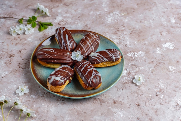 Eclairs oder Kränzchen mit schwarzer Schokolade und weißer Schokolade mit Pudding im Inneren, traditionelles französisches Dessert.