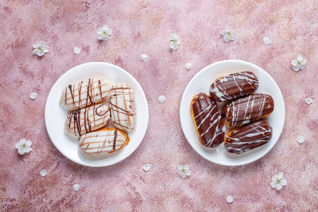 Eclairs oder Kränzchen mit schwarzer Schokolade und weißer Schokolade mit Pudding im Inneren, traditionelles französisches Dessert.