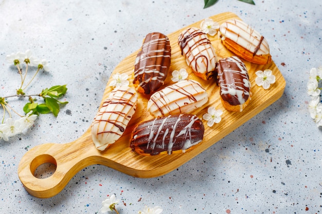 Eclairs oder Kränzchen mit schwarzer Schokolade und weißer Schokolade mit Pudding im Inneren, traditionelles französisches Dessert.