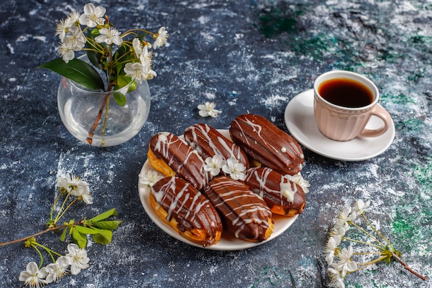 Eclairs oder Kränzchen mit schwarzer Schokolade und weißer Schokolade mit Pudding im Inneren, traditionelles französisches Dessert.