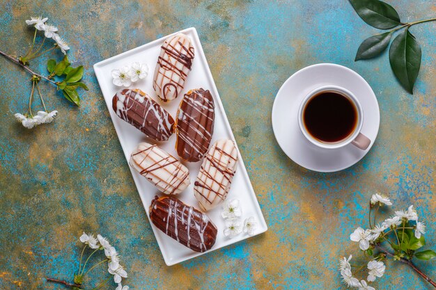 Eclairs oder Kränzchen mit schwarzer Schokolade und weißer Schokolade mit Vanillepudding im Inneren, traditionelles französisches Dessert.