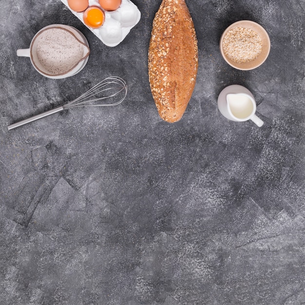 Kostenloses Foto ei; milch; schneebesen ein leib brot; mehl und haferkleie auf konkrete kulisse