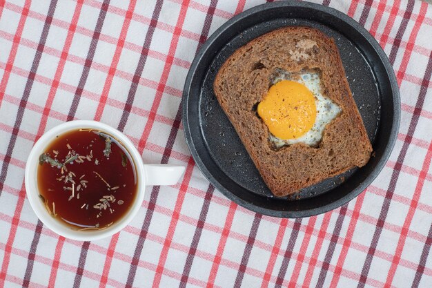 Ei Toastbrot und Tasse Tee auf Tischdecke. Hochwertiges Foto