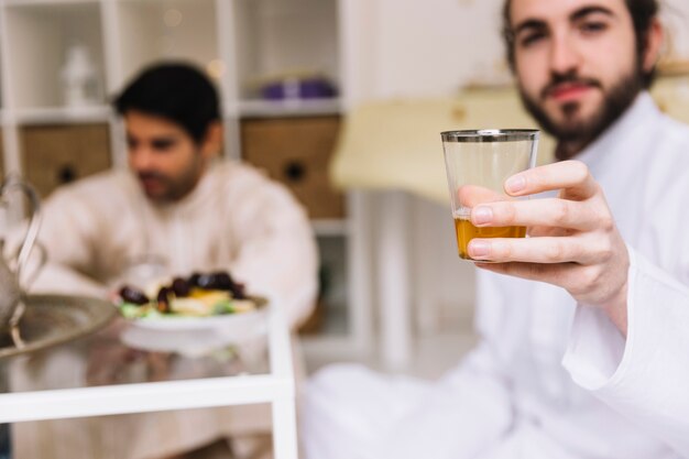 Eid-Konzept mit dem Mann, der Glas Tee zeigt