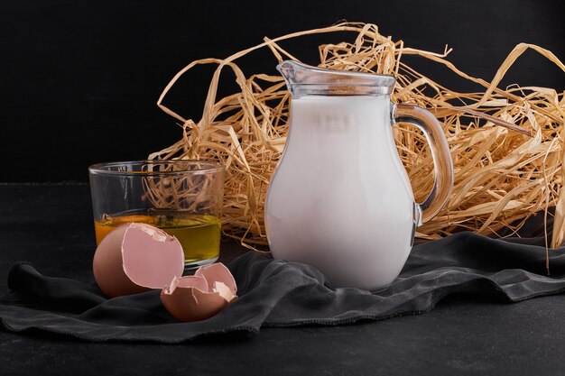 Eier im Nest mit einem Glas Milch auf schwarzem Backgorund.