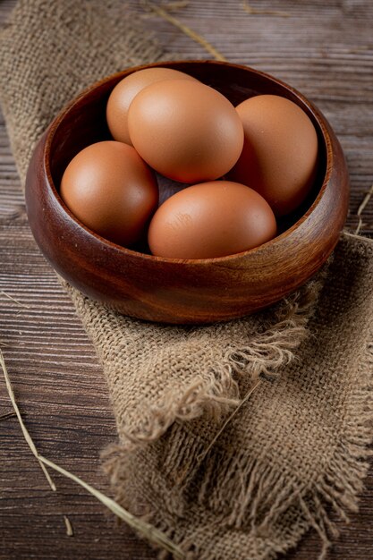 Eier in Tassen auf Sackleinen mit trockenem Gras.