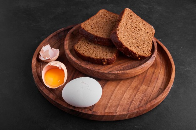 Eier mit Brotscheiben in einer Holzplatte.