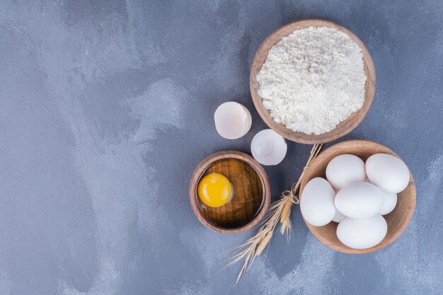 Eier und ein gelbes Eigelb in einem Holzbecher.