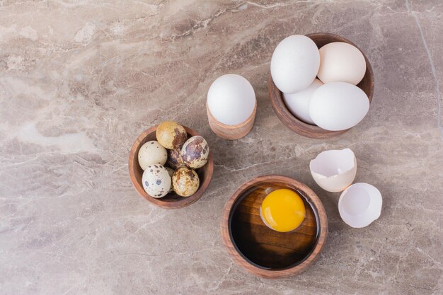 Eier und ein gelbes Eigelb in einem Holzbecher.