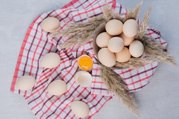 Eier und Federgras pirschen sich in und neben einer Schüssel auf einem Handtuch auf einem Marmortisch an.